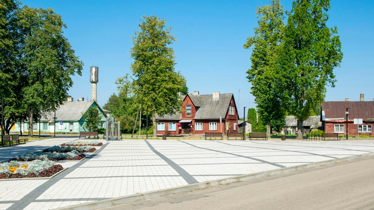 a paved area with trees and houses in the background